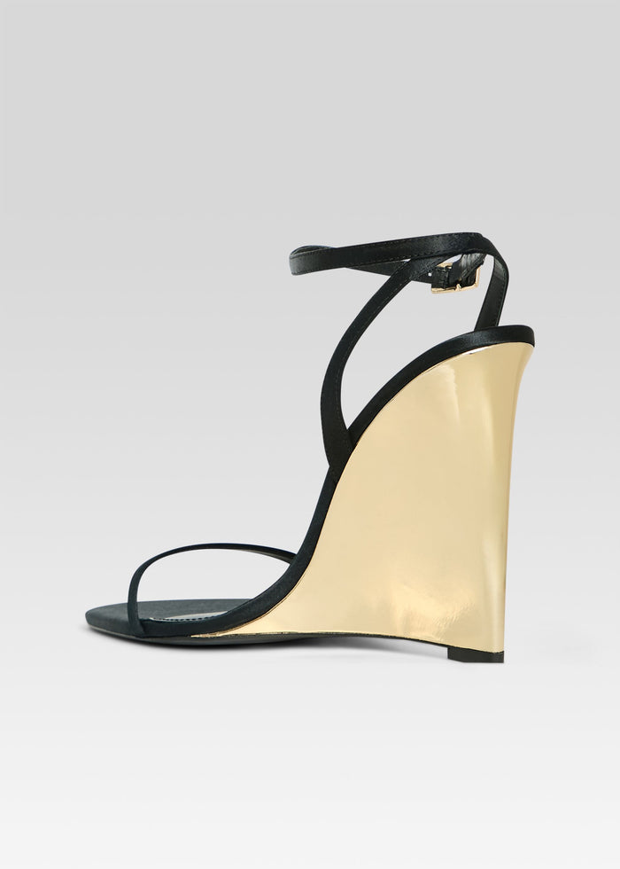 Side view of Nelly Wedge black sandal with tall gold wedge and slim ankle strap. media 5 of 5