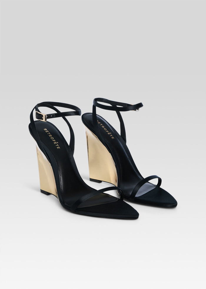Pair of Nelly Wedge black strappy sandals with gold wedge heels photographed together. media 4 of 5