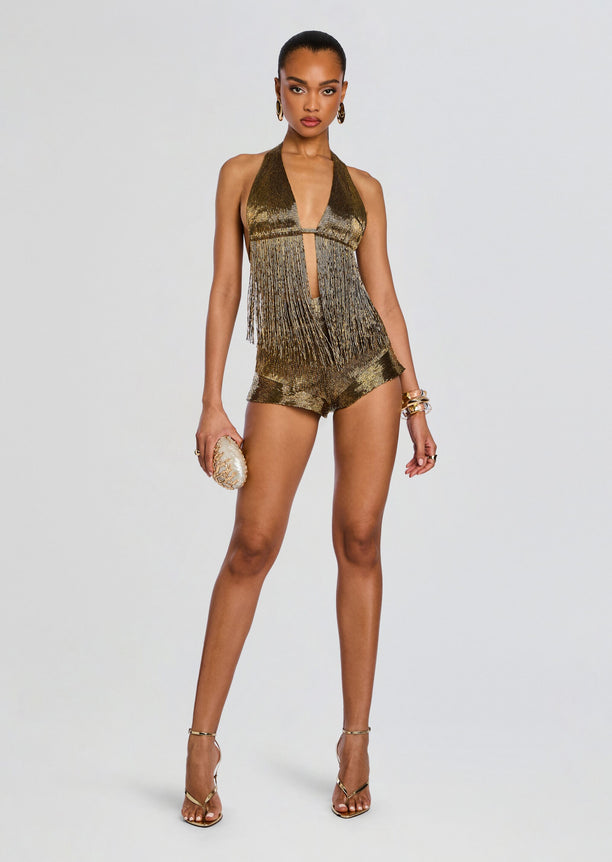 Model wearing a gold fringe halter top with mustard shorts and strappy sandals.