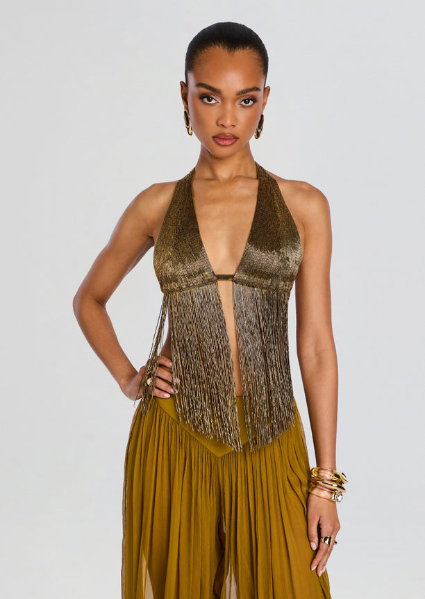 Model wearing a metallic gold embellished fringe halter top with long fringe panels and gold accessories.