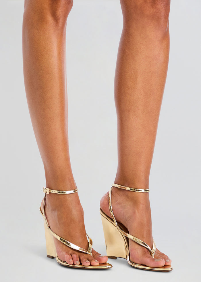 Model wearing gold metallic wedge sandals with a slim ankle strap. media 2 of 5