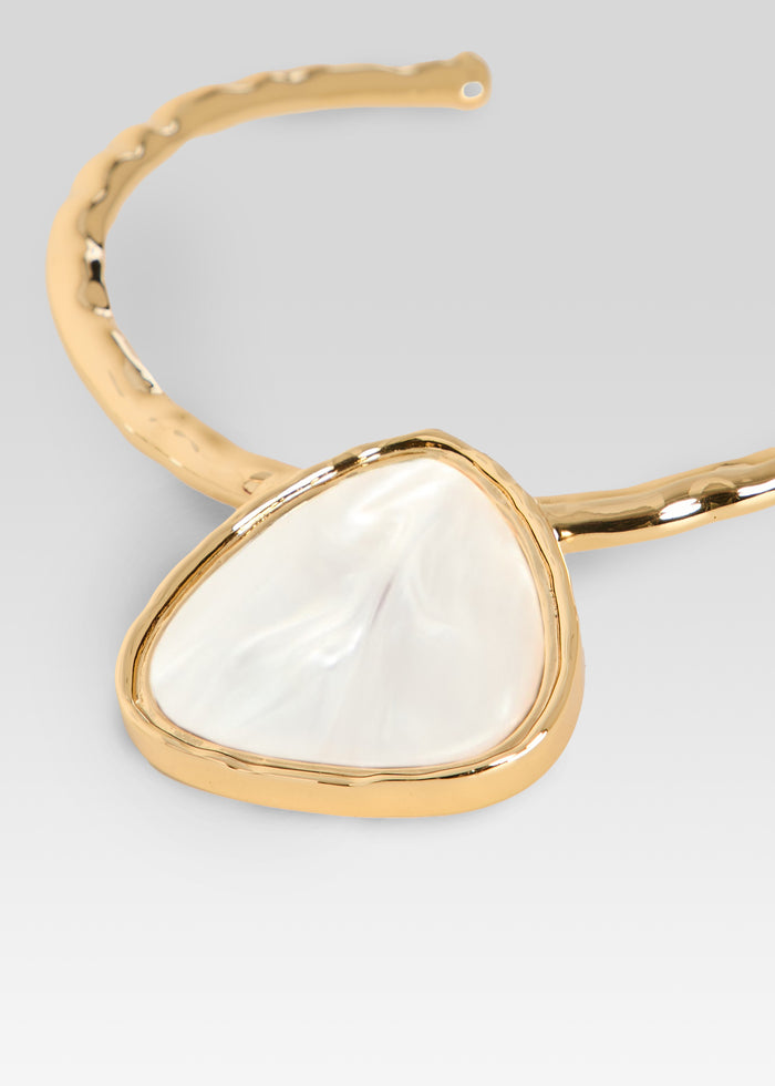 Close-up of gold necklace with triangular white pearl pendant in a rounded bezel setting media 3 of 3