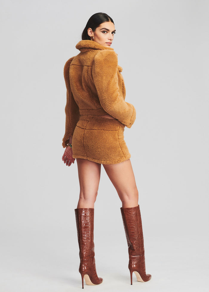 Back view of a model wearing caramel Brie Teddy Jacket and matching shorts with crocodile-embossed knee-high boots. media 4 of 5