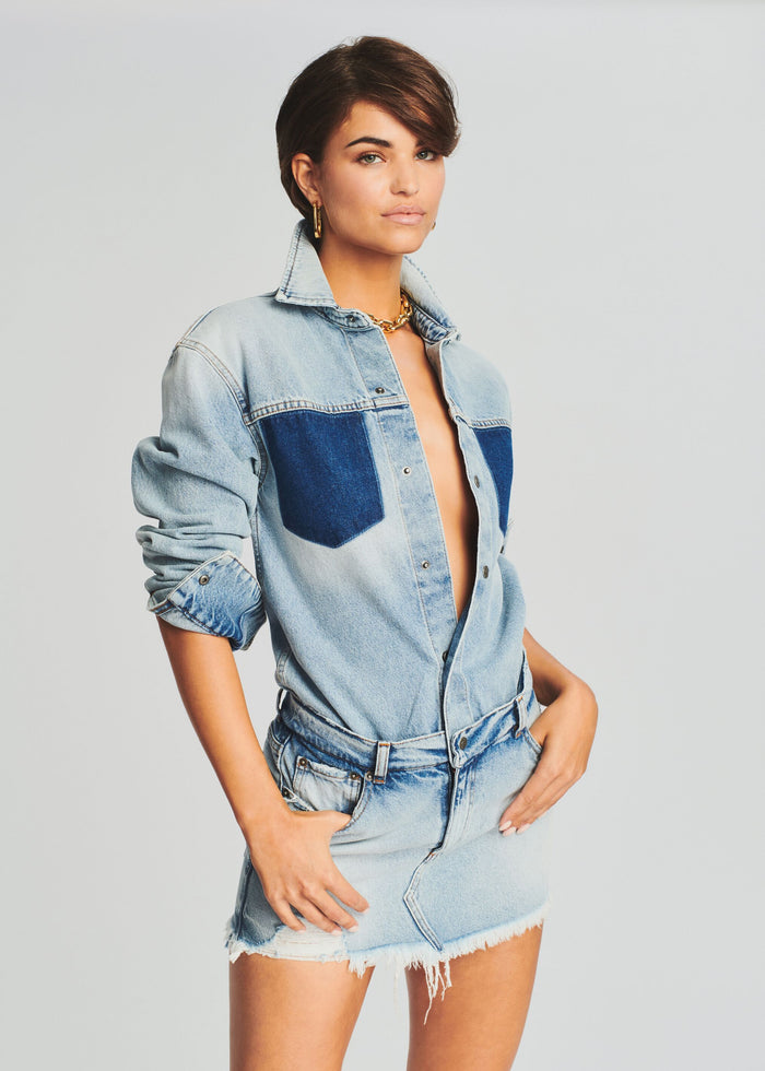 Model wearing a light wash denim shirt with dark pocket panels paired with a frayed mini denim skirt media 2 of 5